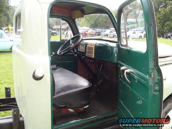 Interior view of a light green and dark green 1948 Ford F-1 pickup truck, showing the dashboard, steering wheel, and seat