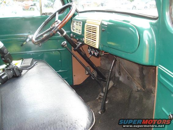Interior of an old truck, showing the steering wheel, dashboard, and floor