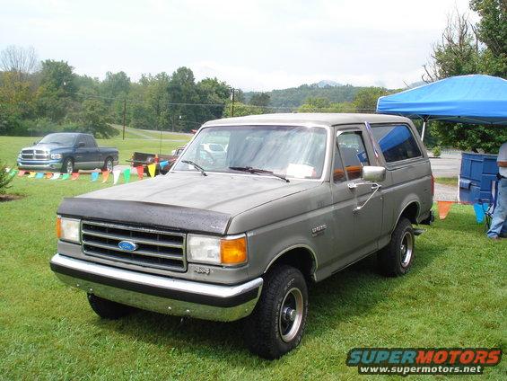 Gray Ford Bronco parked on grass with a blue Dodge Ram pickup in the background