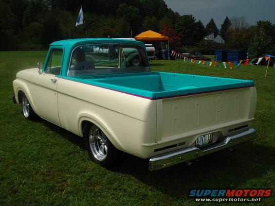 Rear view of a cream and turquoise pickup truck with chrome bumper and aftermarket wheels
