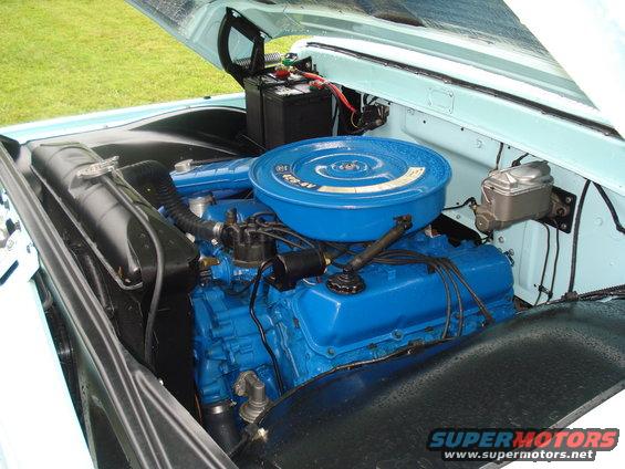 Engine bay with blue painted V8 engine, air cleaner, battery, and radiator