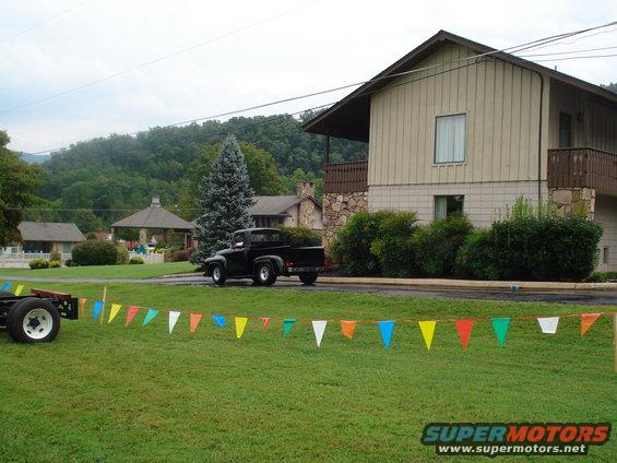 Black pickup truck parked on a street in front of a house, with colorful pennant flags in the foreground