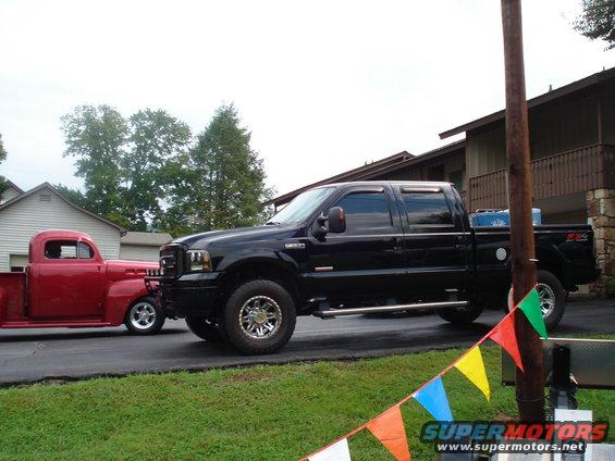 Black Ford Super Duty pickup truck parked next to a red classic pickup truck