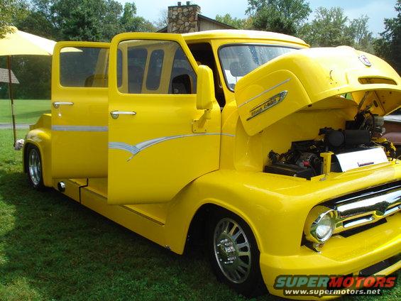 Yellow custom pickup truck with doors open and hood up, showing engine