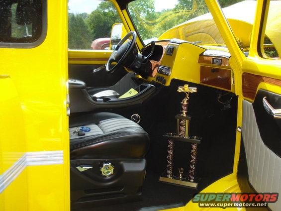 Yellow truck interior with black and gray seats, wood trim, and a trophy on the floor