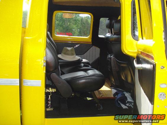 Yellow truck interior with black leather seats, a hat on the passenger seat, and a trophy on the floor