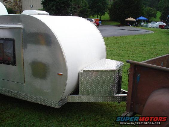 Teardrop trailer with diamond plate accents, attached to a vintage truck bed
