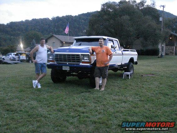 Two guys with a lifted blue and white Ford F-Series truck. Other trucks in background