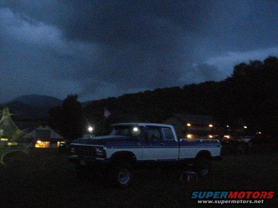 Blue and white Ford F-Series truck, lifted, parked outdoors at dusk
