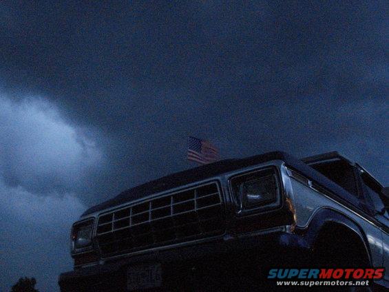 Dark blue truck with chrome grille and American flag on roof, front view
