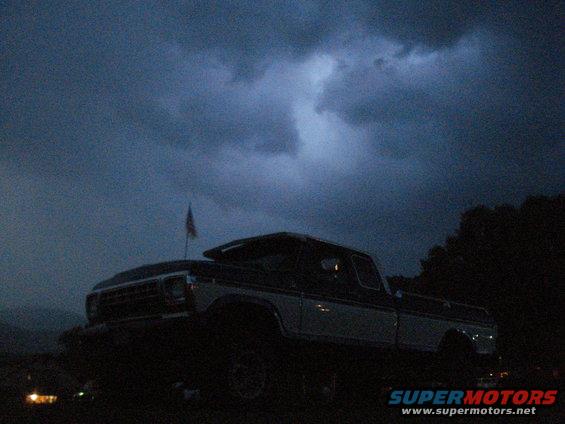 Pickup truck with American flag on antenna, dark stormy sky