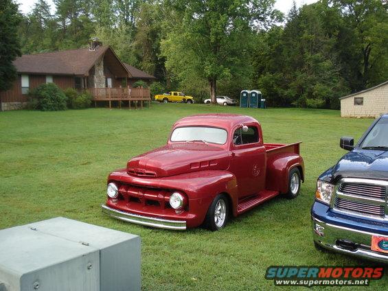 Red classic pickup truck parked on grass next to a blue modern pickup truck