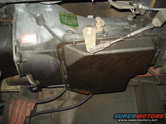 Transmission pan with linkage and an 'IMPORTANT' sticker. Numbers '24' are visible on the casing