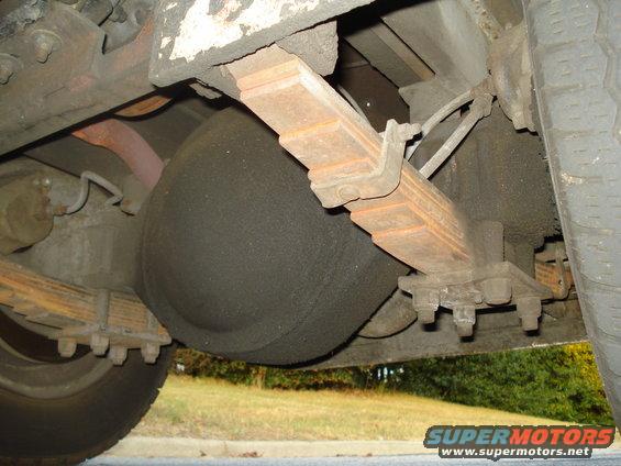 Undercarriage view of leaf springs and a large black air suspension bag mounted above the rear axle