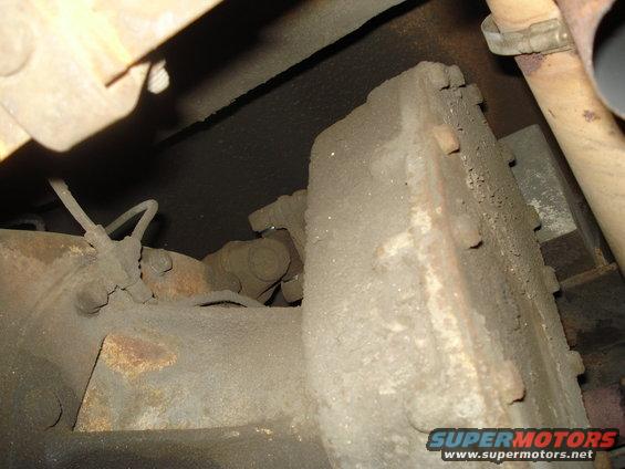 close-up of rusty drivetrain parts under a vehicle, possibly a driveshaft and differential housing
