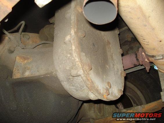 Underside view of a rusty differential housing and exhaust pipe on a vehicle