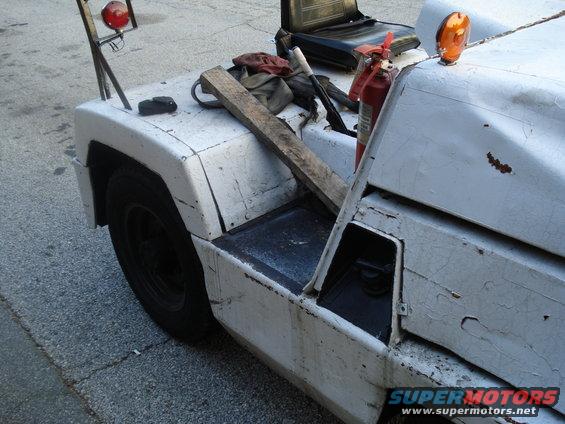 White tow tractor side view with orange beacon and fire extinguisher