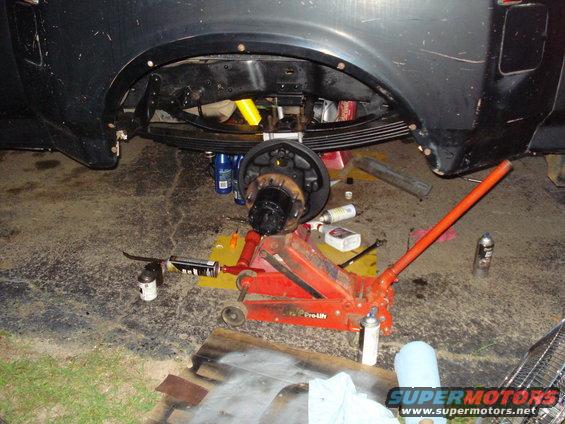 Truck rear axle is jacked up with tools and parts scattered around