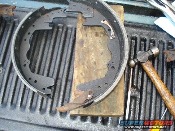 Drum brake shoes and hardware laid out on a truck bed with a hammer