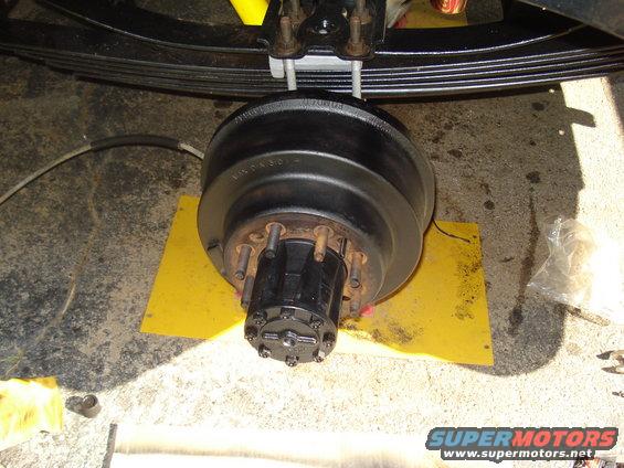 Close-up of a truck's rear axle hub and brake drum assembly, with leaf springs visible above
