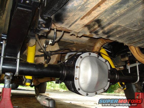 Underside view of a rear axle assembly with yellow shock absorbers and leaf springs