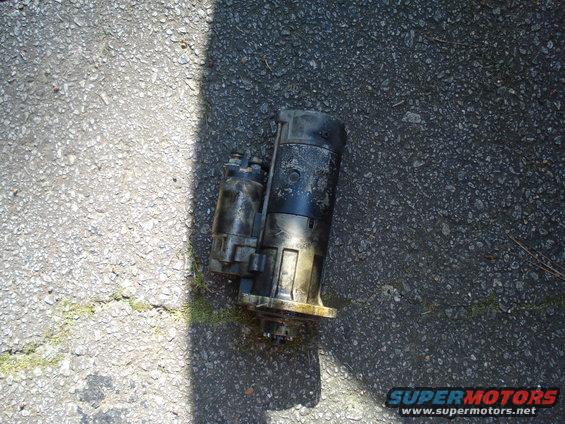 Black starter motor on asphalt