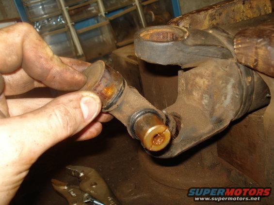 Close-up of a rusty universal joint part being held by a hand