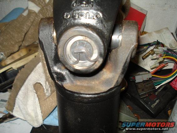 Close-up of a driveshaft U-joint with a c-clip visible. Wires and other parts are in the background