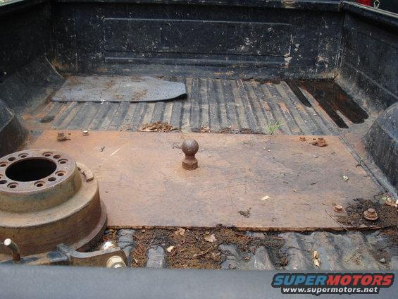 Truck bed with a fifth wheel hitch ball and a brake drum. Some debris is present
