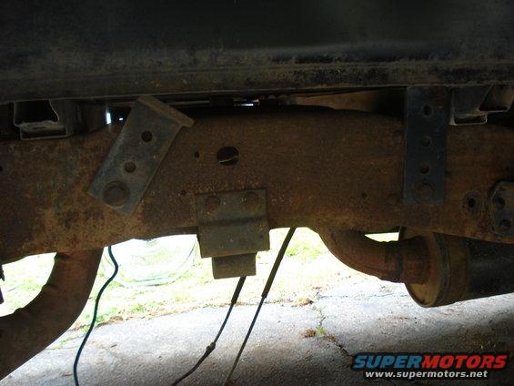 Rusty truck frame with visible suspension components and exhaust pipe