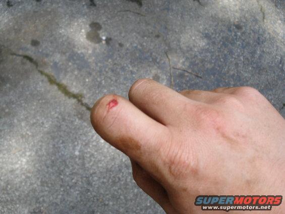 Cut finger with blood on it, on a concrete surface with oil stains