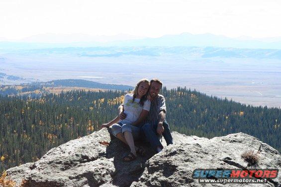 Couple sitting on a rock overlooking a valley and mountains
