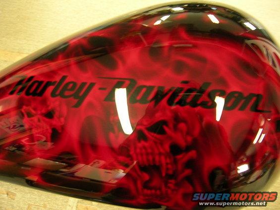 Motorcycle gas tank with red and black flame and skull graphics. "Harley-Davidson" text is visible