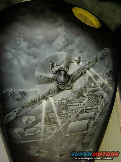 Motorcycle gas tank airbrushed with a scene of WWII fighter planes bombing a city