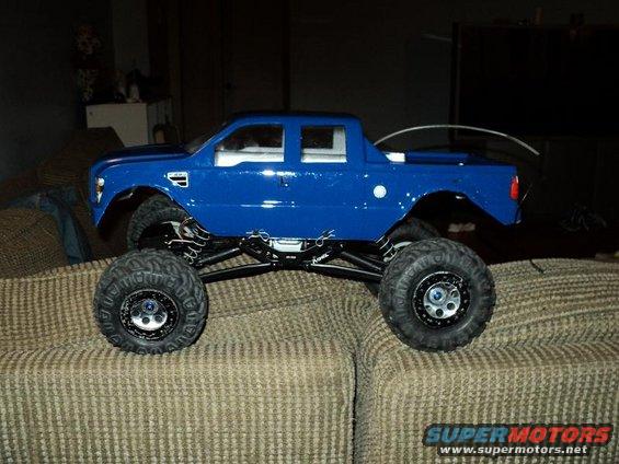 Blue RC monster truck with large tires sitting on a couch