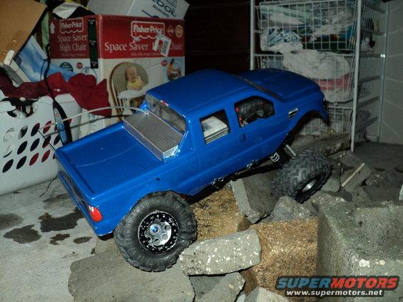 Blue RC rock crawler truck with large tires on concrete blocks