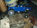 2008 Ford F-250 - A blue RC truck is shown on a rocky terrain, with household items in the background.