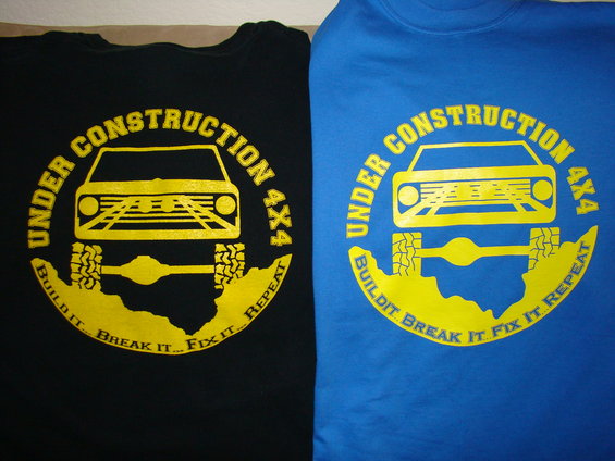 Black and blue t-shirts with yellow graphic of an off-road vehicle, text reads "UNDER CONSTRUCTION 4X4 BUILD IT. BREAK IT. FIX IT. REPEAT."