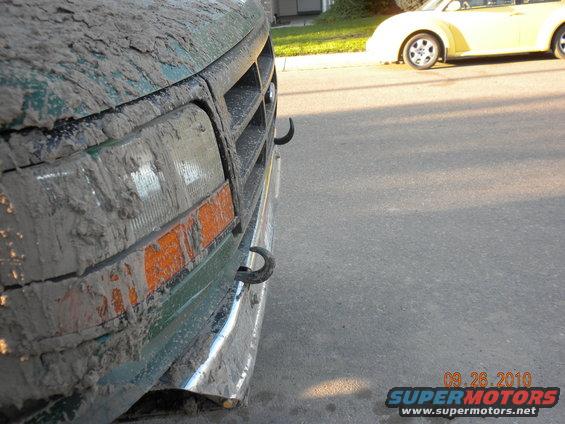 Green Ford Bronco covered in mud, front quarter panel and grille visible