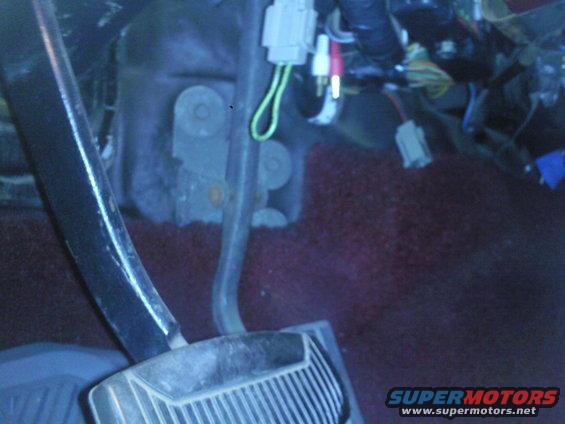 Close-up of vehicle pedals and wiring harness in the footwell