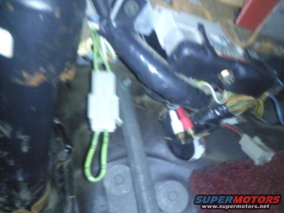 Close-up of vehicle wiring harness with white connector and green wires