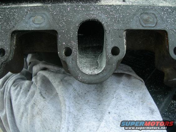 Close-up of a metal engine intake manifold with debris inside
