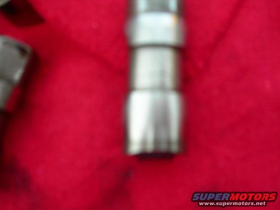 Metal engine component with stacked sections on red fabric, with a Supermotors.net watermark
