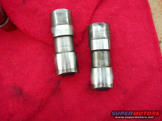 Two metal engine lifters on a red cloth