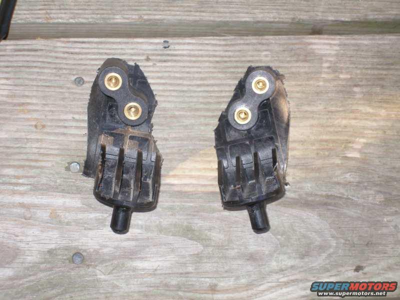 Two black rubber engine mounts with brass fittings on a wooden surface