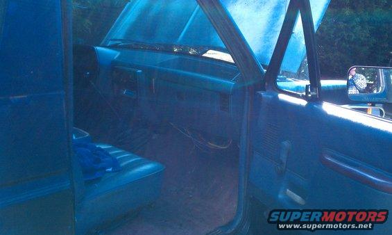 Interior of a blue truck with the hood up. Shows dashboard, seats, and door panel