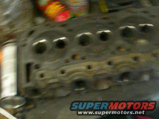 Close-up of an engine cylinder head with SuperMotors.net logo visible