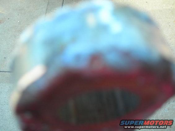 Close-up of a rusty, red-painted exhaust pipe section with a blueish tint