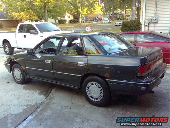 Dark sedan parked next to a white pickup truck, with a red car visible behind it