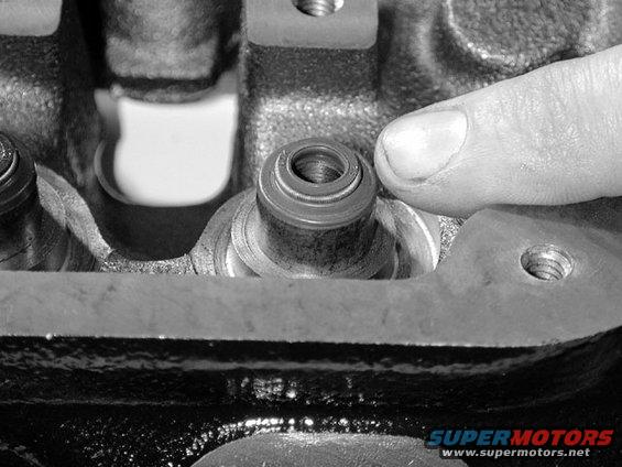 Close-up of engine valve stem seal with finger pointing